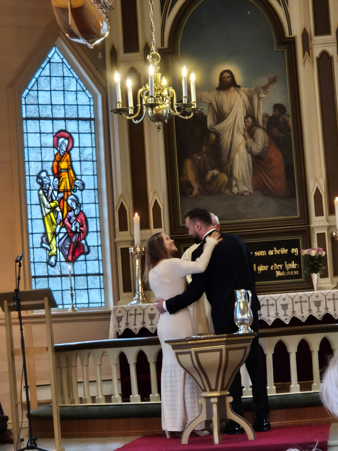 Brudeparet står ved alteret og ser glad på kvarandre. Ho i kvit kjole og han i dress