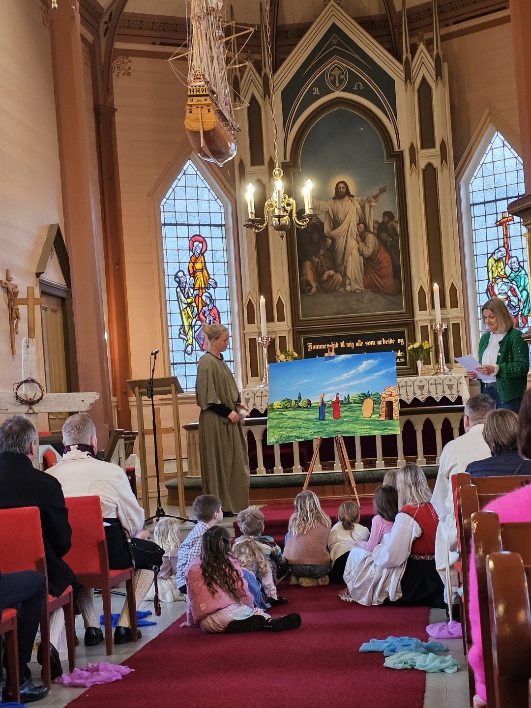 Barnas påskedag. Barn sitter foran trappen. hører på påskefotelling og ser på flanellograf
